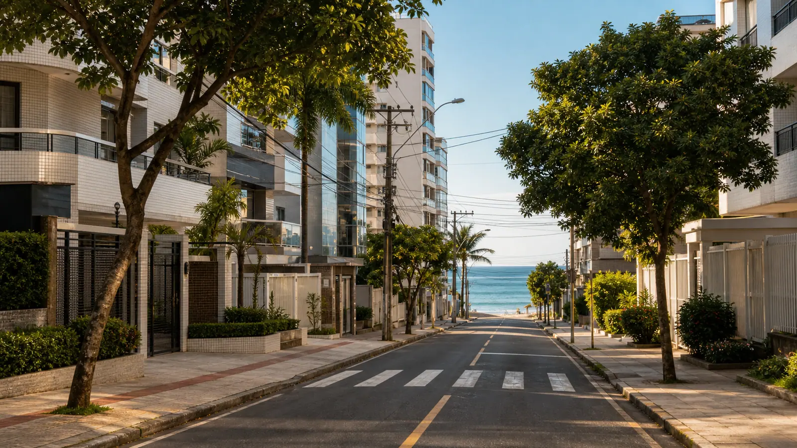 Rua residencial perto da orla de Vila Velha com predios e calcada arborizada
