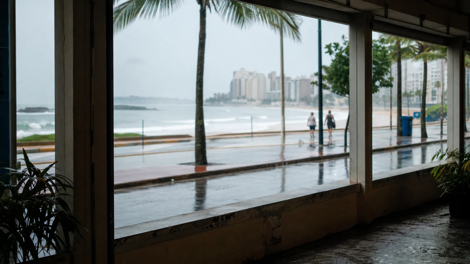 Janela coberta em Guarapari mostrando chuva sobre rua perto da praia